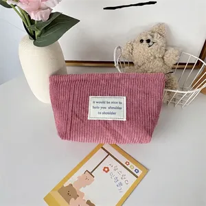 Detailed texture of pink corduroy makeup bag with minimalist white fabric label