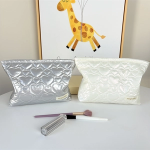 Detail of silver and white heart-quilted PU makeup bags with metallic finish