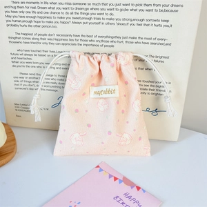 Detail of pink corduroy drawstring bag with cute rabbit print and woven brand label