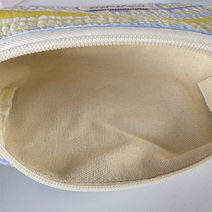 Detail of striped knitted pouch showing canvas interior and durable nylon zipper