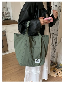 Detail of green nylon tote bag with dual handles and large side pocket for daily commute