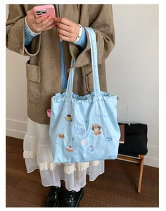 Close-up of a blue drawstring tote bag featuring cute puppy and dessert embroidery