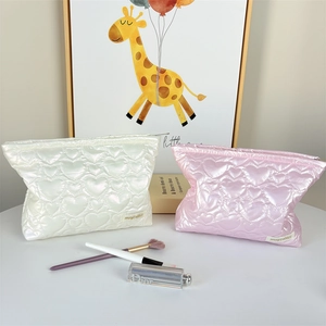 Detailed view of heart quilted satin toiletry bags in pearl white and pink finish
