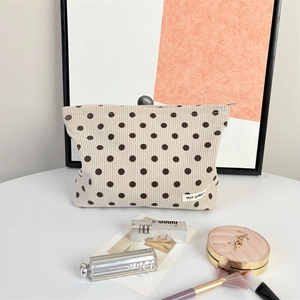 Detailed texture of beige corduroy cosmetic bag with brown polka dots and label