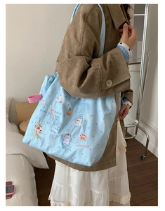 Detail of cute cat embroidery and polka dot fabric on a light blue canvas tote bag