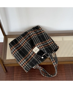 Detail of vintage plaid tote bag with textile texture on a woven wooden bench
