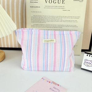 Pink and blue striped fabric cosmetic bag with label on vintage magazine background