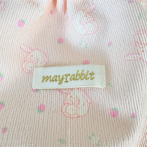Macro view of pink corduroy fabric with cute bunny print and embroidered brand label