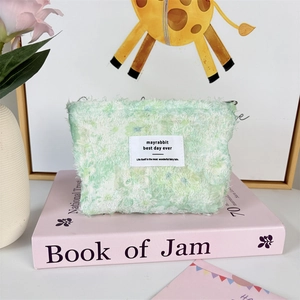Detailed view of mint green plush chiffon floral makeup bag with woven brand label