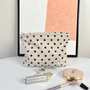 Close-up of beige corduroy polka dot makeup bag showing soft ribbed texture and label