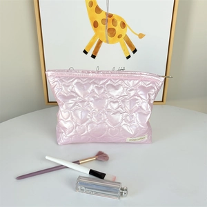 Detail of pink quilted makeup bag with heart pattern and pearlescent finish
