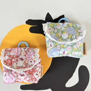 Close-up of floral fabric earphone pouches with lace trim and blue hanging hooks