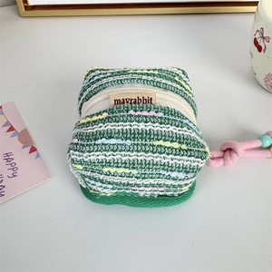 Macro detail of a green knit earphone case with a pink cord and beaded lanyard