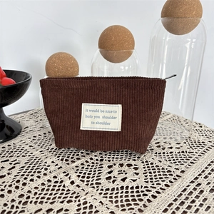 Detail of dark brown corduroy makeup bag showing ribbed texture and fabric label
