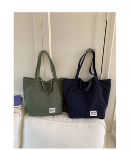 Detail of large nylon tote bags in olive and navy with Beyou Merci label