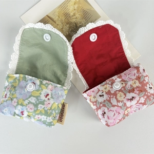 Detail of floral fabric earphone pouches with white crochet lace and snap button closure
