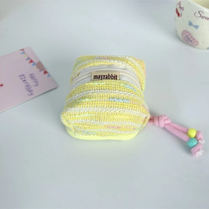 Macro shot of yellow tweed mini earphone pouch with drawstring beads and brand label