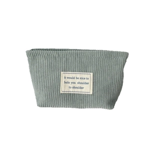 Minimalist grey-blue corduroy makeup bag with woven label on a clean white background
