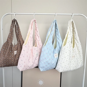 Detailed row of floral print tote bags in four colors hanging on a white metal rack