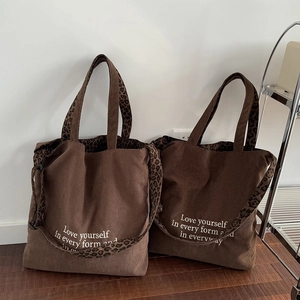 Bolso tote de pana marrón con asas de leopardo y frase blanca decorativa en el frontal