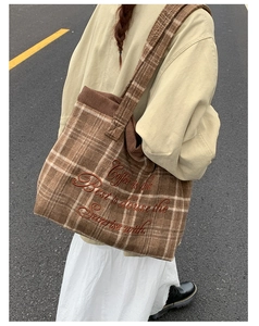 Brown plaid tote bag with embroidered quote shown on model in an outdoor setting