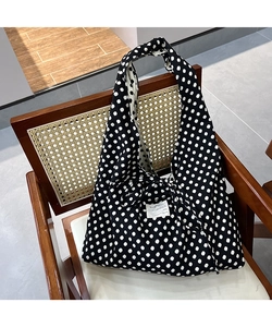 Detailed view of the black canvas tote bag with white polka dots and tie-knot handle