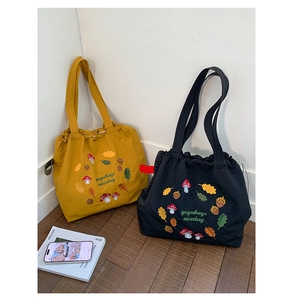 Detail of mushroom and acorn embroidery on drawstring nylon tote bag with brand lettering