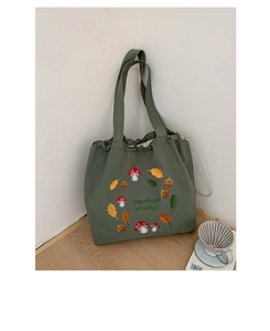 Detailed close-up of mushroom and forest embroidery on green nylon tote bag