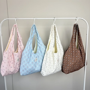 Floral quilted tote bags in pink, blue, beige and tan hanging on a metal rack