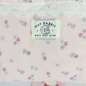 Detail der rosa Cord-Tragetasche mit Blumendruck, Spitzenbesatz und Stoffetikett