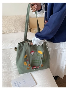 Detail of mushroom embroidery on a green nylon tote bag with drawstring closure
