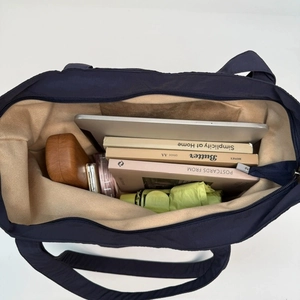 Navy blue nylon tote bag showing spacious interior with books and tablet on white background