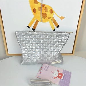 Macro detail of silver quilted PU cosmetic bag with metallic texture and brand label