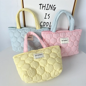 Detail of colorful quilted tote bags in yellow, pink and blue showing bubble stitch texture