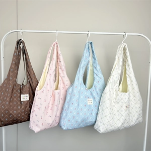 Four floral print tote bags in brown pink blue and beige hanging on a metal rack