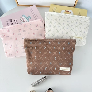 Three corduroy bow makeup bags in floral and quilted patterns with top zip closure