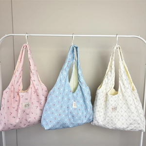 Detailed view of floral canvas tote bags in pink, blue and white on a minimalist hanger