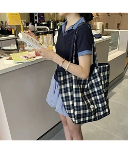 Détail du grand sac cabas en toile à carreaux noir et blanc avec écusson logo latéral