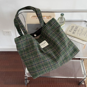 Green and blue checkered canvas tote bag with long handles in a lifestyle setting