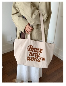 Detail of corduroy tote bag showing Brave new world embroidery and striped texture