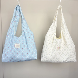 Detail of floral canvas tote bags with tulip prints and woven texture brand label