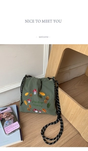 Close-up of forest green nylon crossbody bag featuring cute mushroom embroidery and woven straps