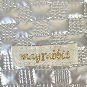 Macro detail of silver quilted metallic fabric with an elegant brand woven label