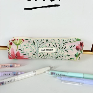 Detalle del bordado floral en un estuche de lona con etiqueta de marca y cremallera