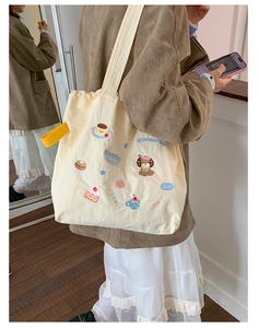 Detail of off-white canvas tote featuring cute puppy embroidery and yellow ribbon accent