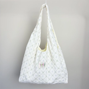 Detailed view of quilted diamond pattern with floral prints and small green bows on bag