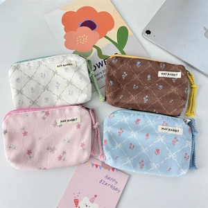 Detail of four floral corduroy pouches in white, brown, pink, and blue with zipper pullers