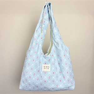Detail of blue floral canvas tote bag with tulip patterns and woven logo patch
