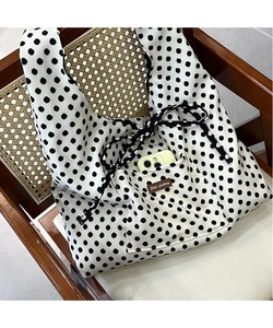 Detail shot of canvas tote bag featuring black polka dots and Star-picking leather patch