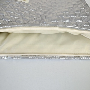 Detail of silver quilted makeup bag with smooth zipper and cream fabric lining